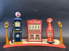 A Marx Toys tinplate garage forecourt comprising two petrol pumps flanking a central oil cabinet.