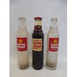 Three Shell X-100 glass oil bottles.