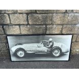 A framed and glazed photographic print of believed Nuvolari driving at speed, 40 x 19 1/2".