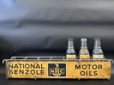 A National Benzole (NBC) wall mounted oil bottle rack with three pint bottles, two with caps.