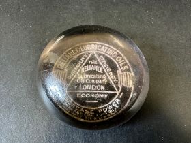 A Reliance Lubricating Oils glass paperweight.