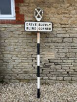 A Scottish Automobile Club 'Drive Slowly Blind Corner' roadside post, sign displays signs of repair,