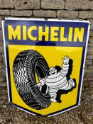 A large Michelin Tyres pictorial enamel advertising sign depicting Mr Bibendum rolling a tyre,