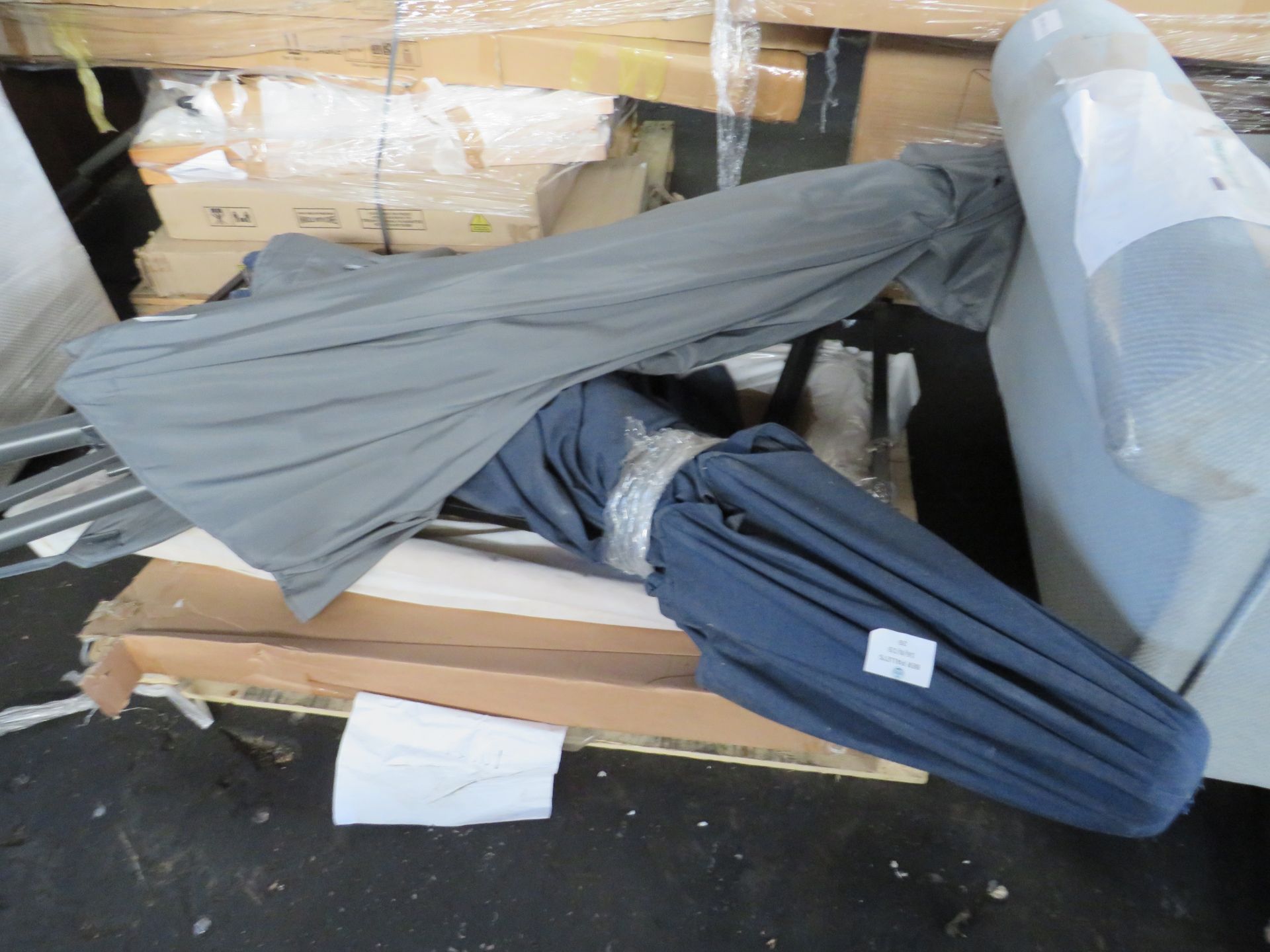 pallet of table legs and 2 parasols. Unchecked