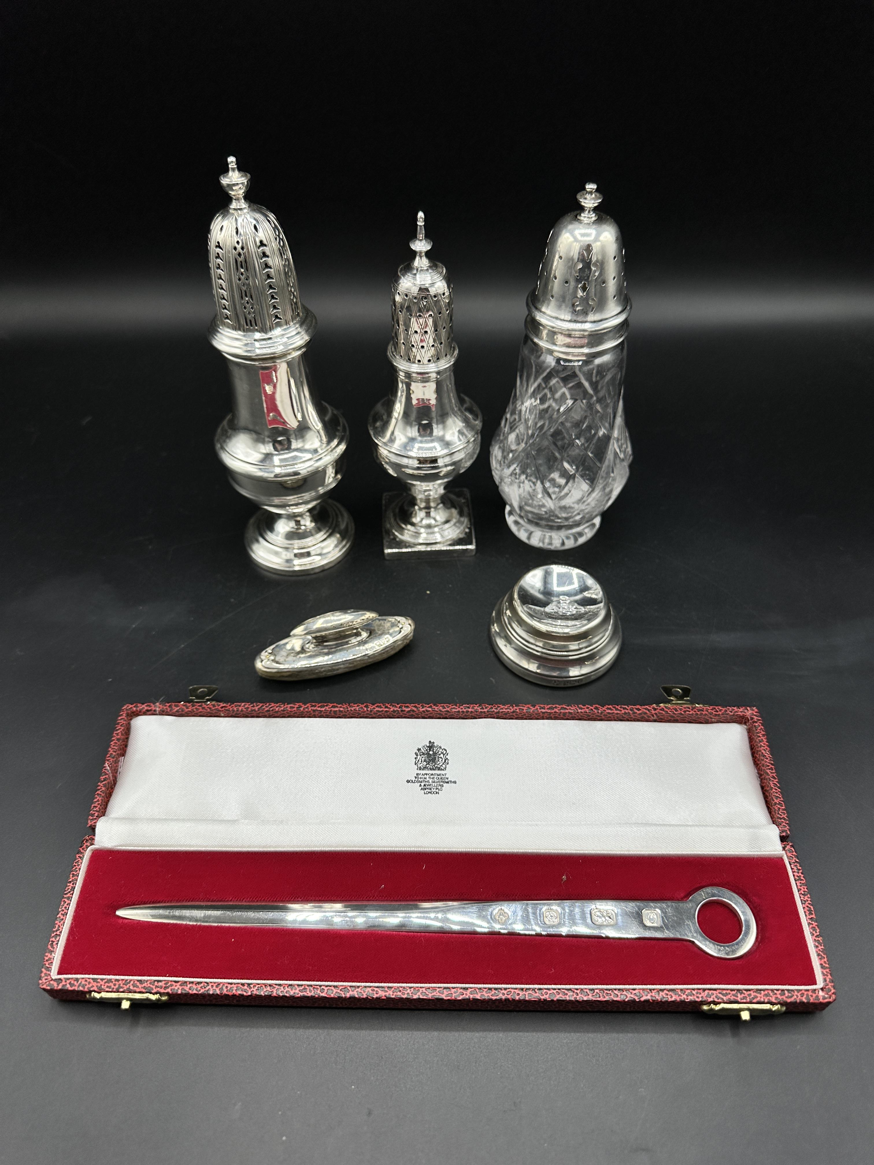 Two silver sugar casters together with a glass and silver sugar caster