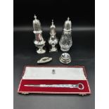 Two silver sugar casters together with a glass and silver sugar caster