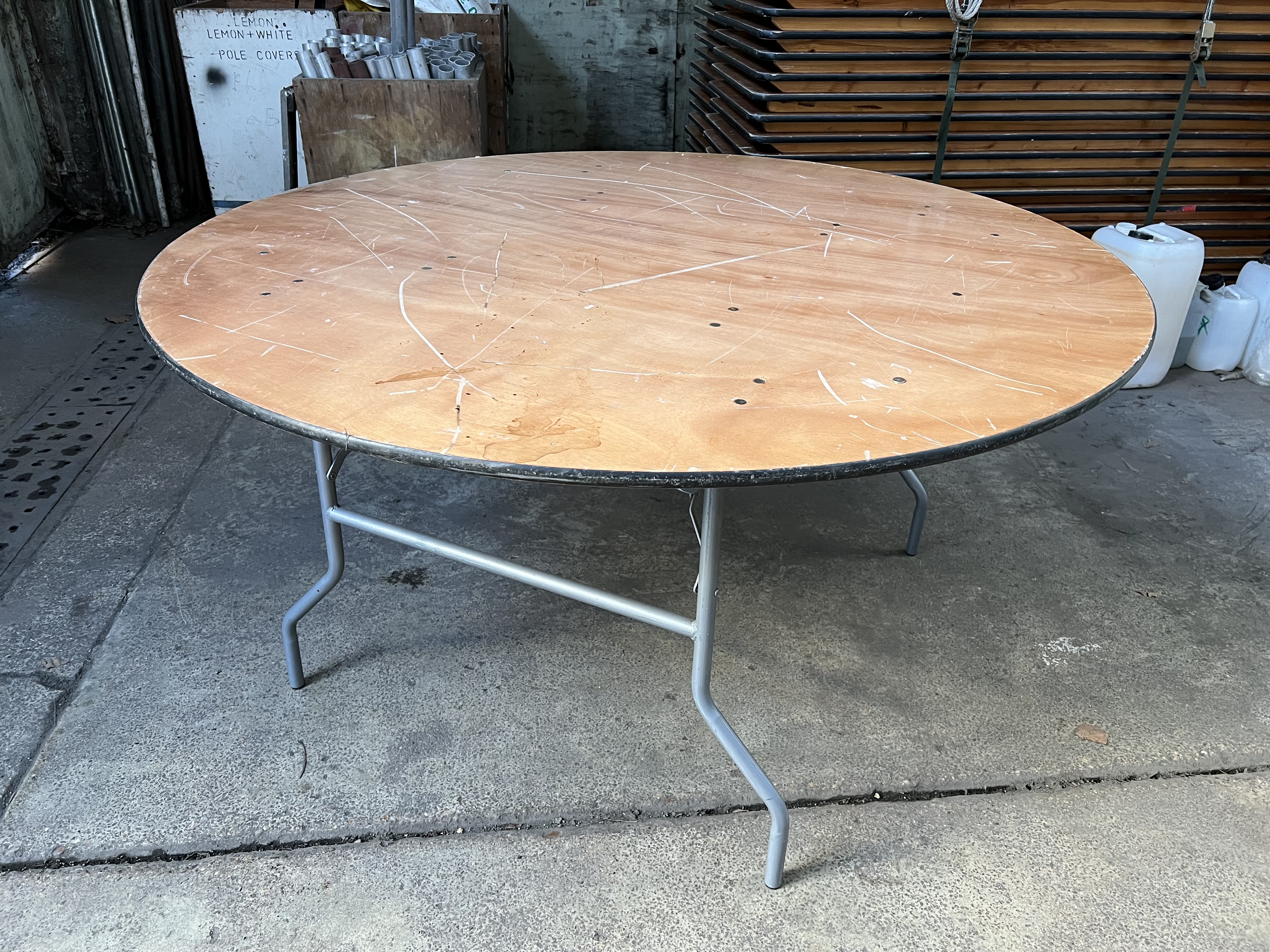 16 no 5ft diameter round tables with folding legs and plywood top. This lot is subject to VAT.