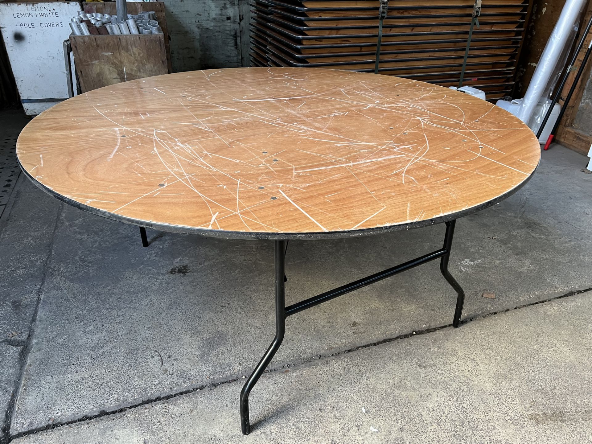 10 no 5ft 6in diameter round tables with folding legs and plywood top. This lot is subject to VAT.