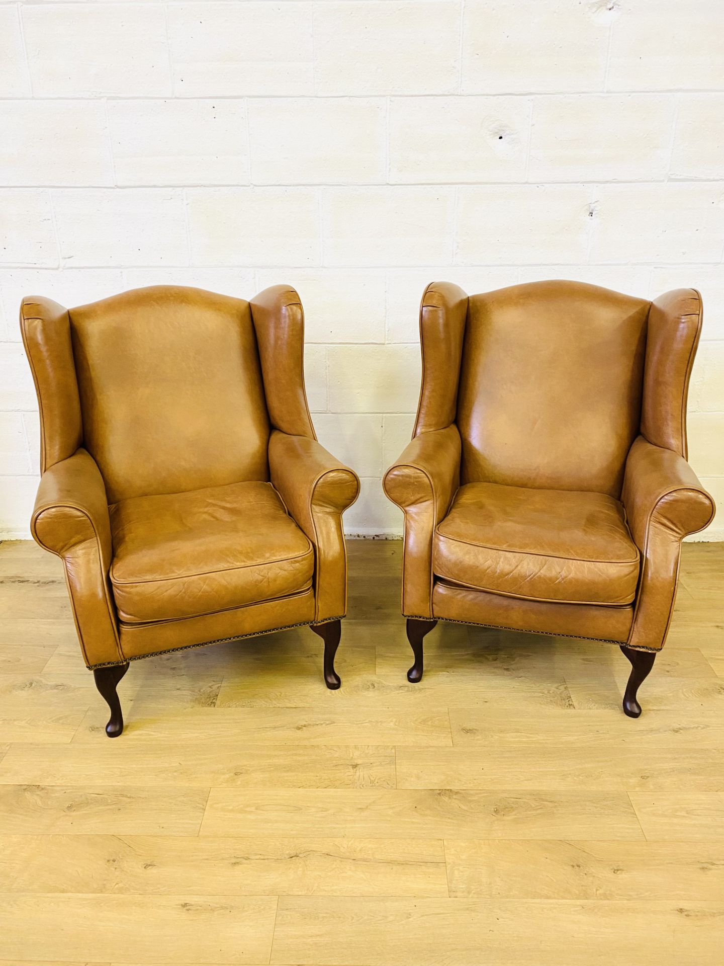 Pair of brown leather style wingback armchairs