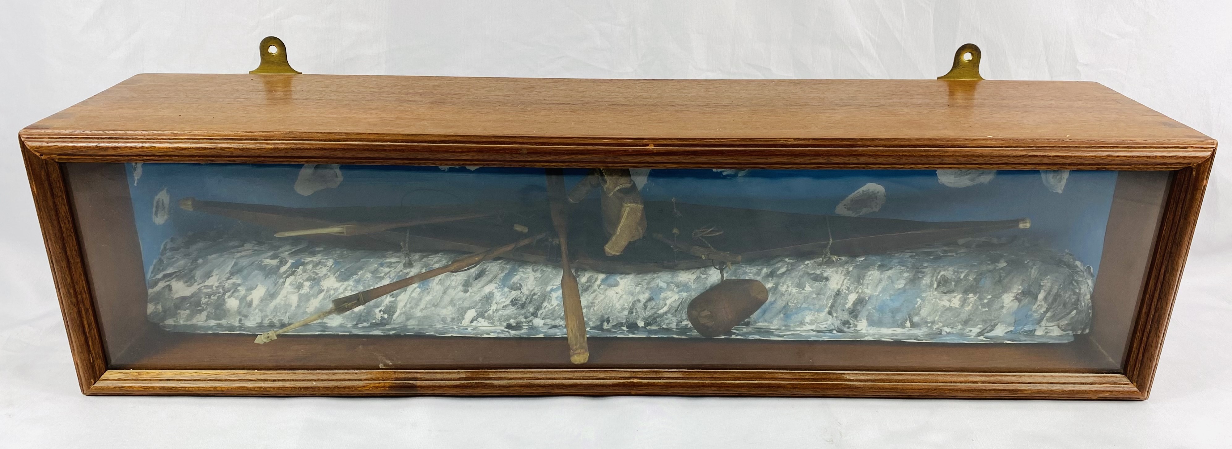 Glass fronted case containing a model Inuit kayak