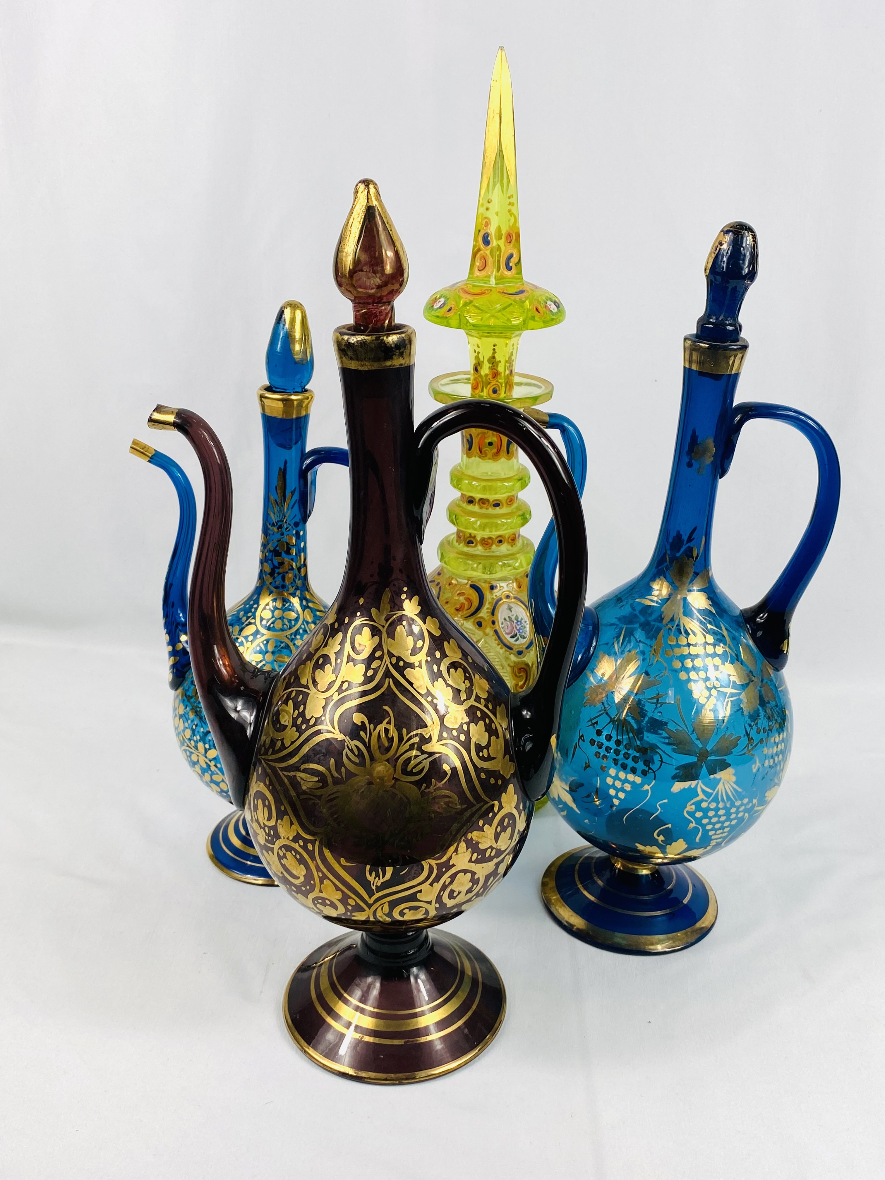 Three Persian rode water bottles together with a yellow glass decanter