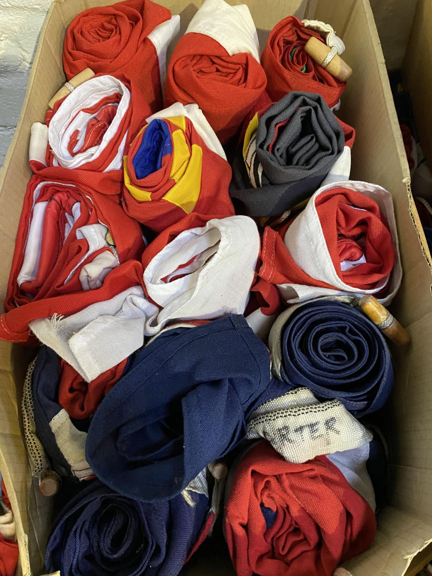 A box of fourteen flags from five countries. This lot is subject to VAT.