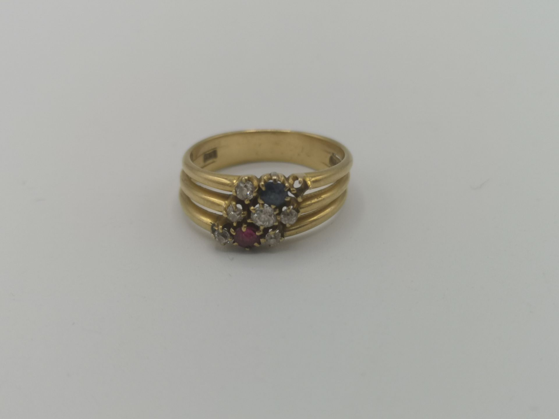 18ct gold triple ring set with six diamonds, a ruby and a sapphire