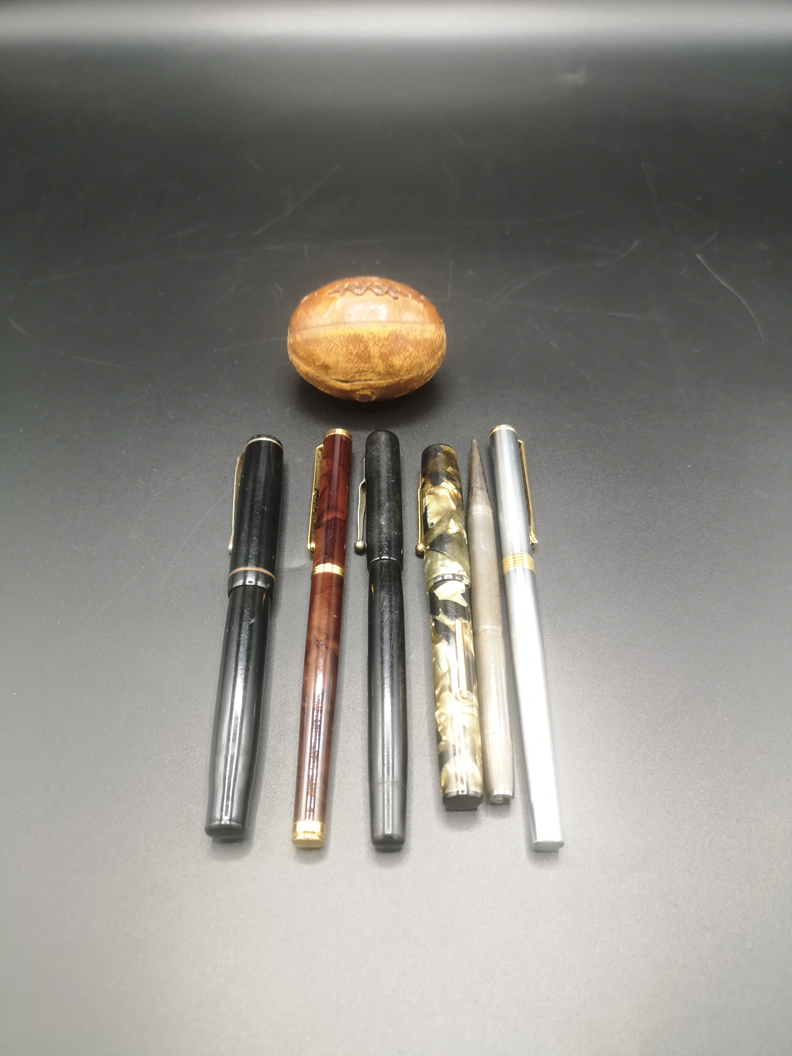 Four fountain pens, a brass inkwell in a leather rugby ball style case and other items