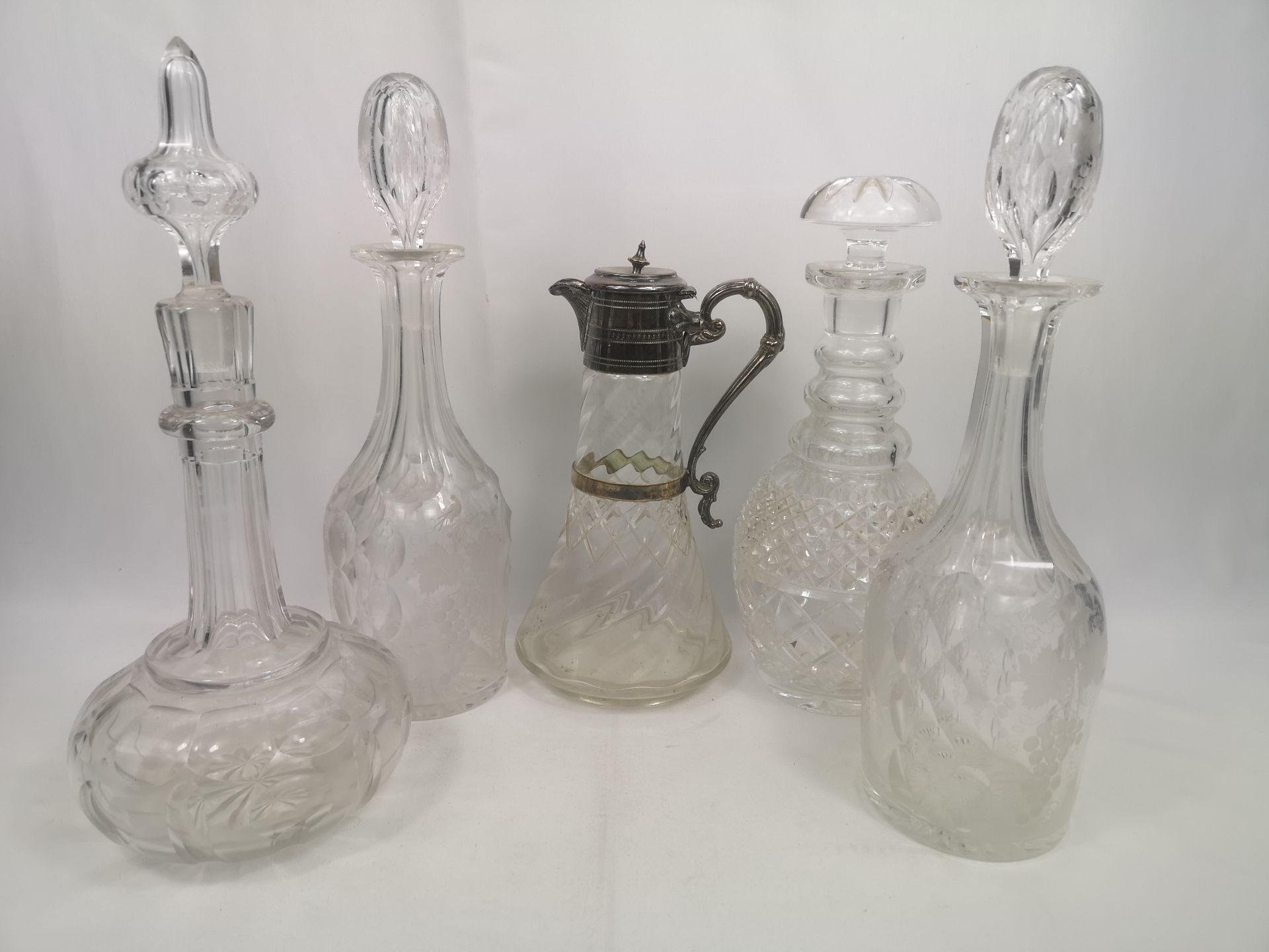 Four glass decanters together with a glass claret jug