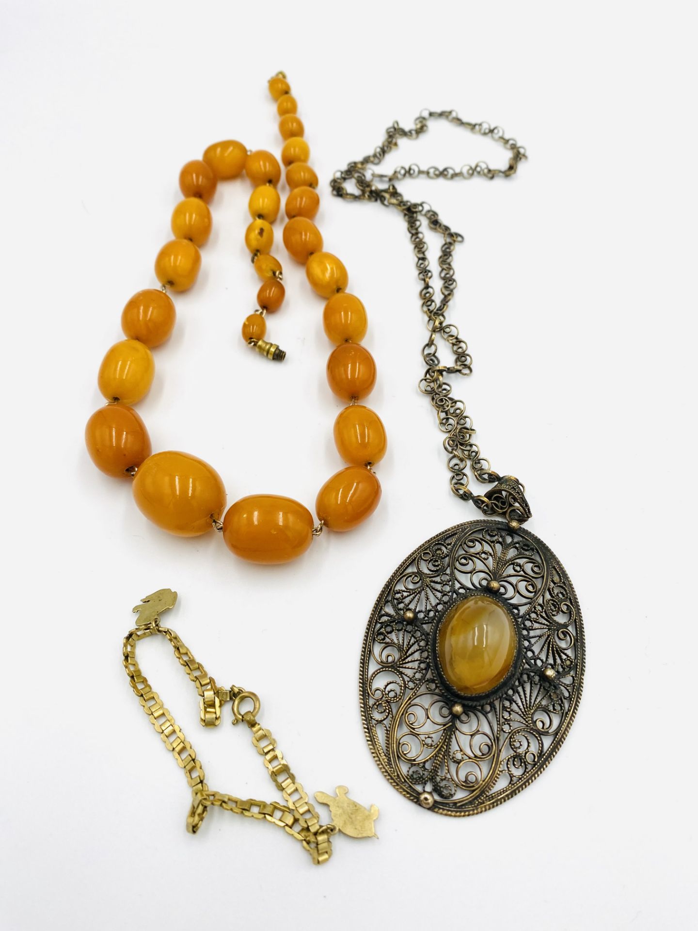 Amber bead necklace; filigree pendant necklace and a child's charm bracelet