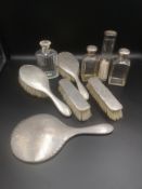 Four silver backed dressing table brushes together with silver topped bottles