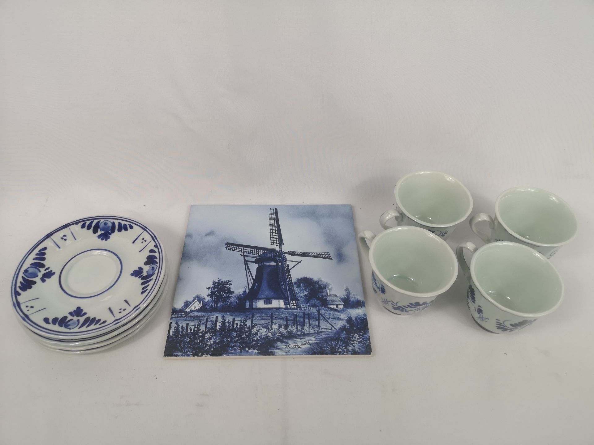 Four Delft cups and saucers together with a Delft tile