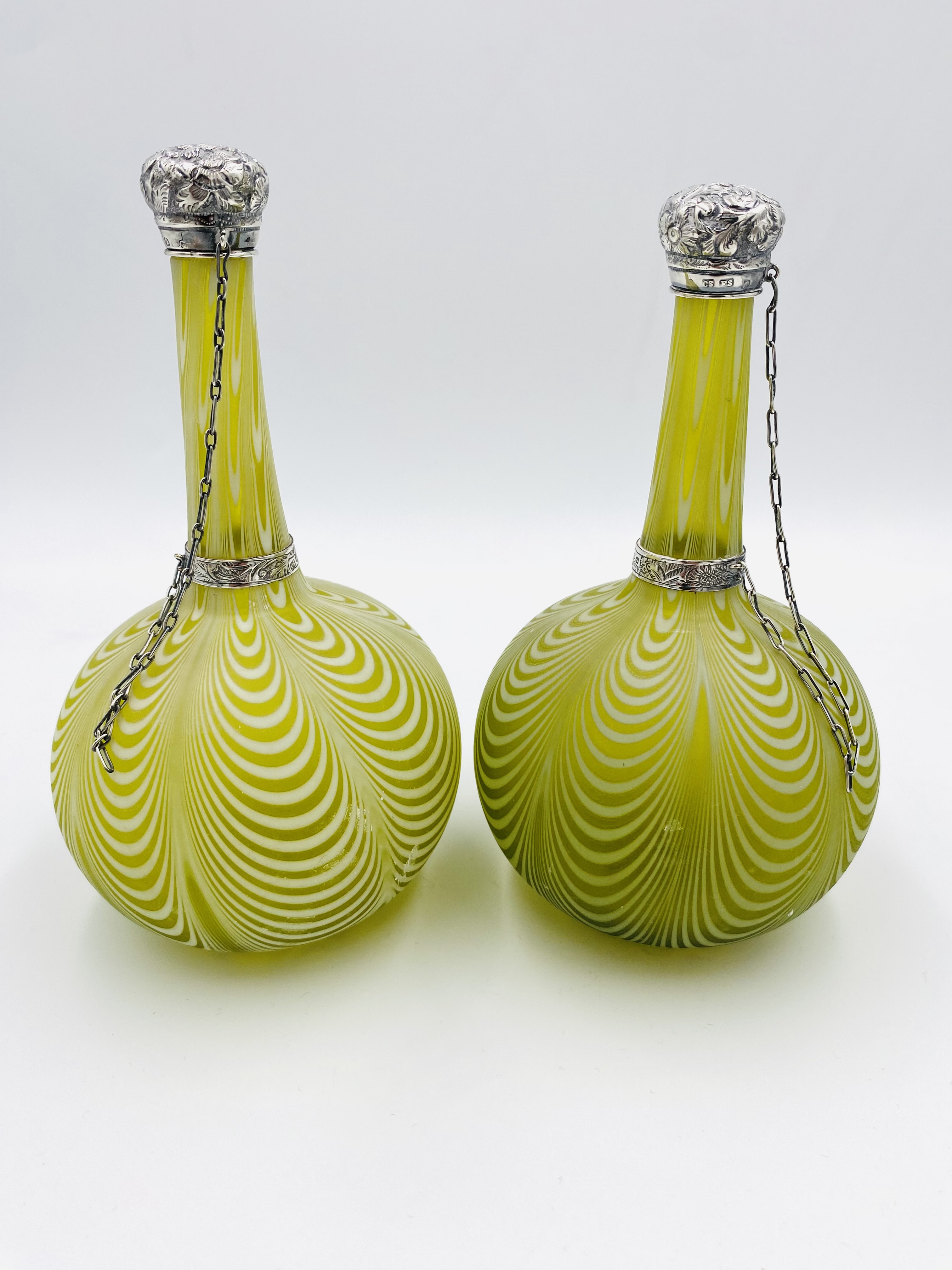 A pair of glass perfume bottles with silver tops