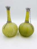 A pair of glass perfume bottles with silver tops