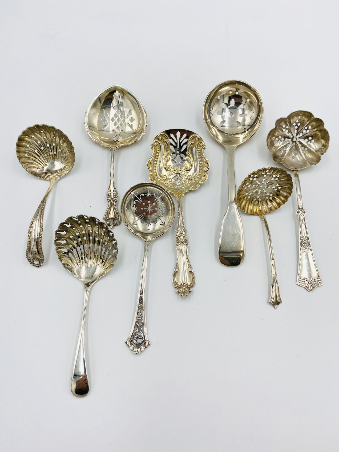 A collection of silver sugar sifters and a silver plated sugar sifter