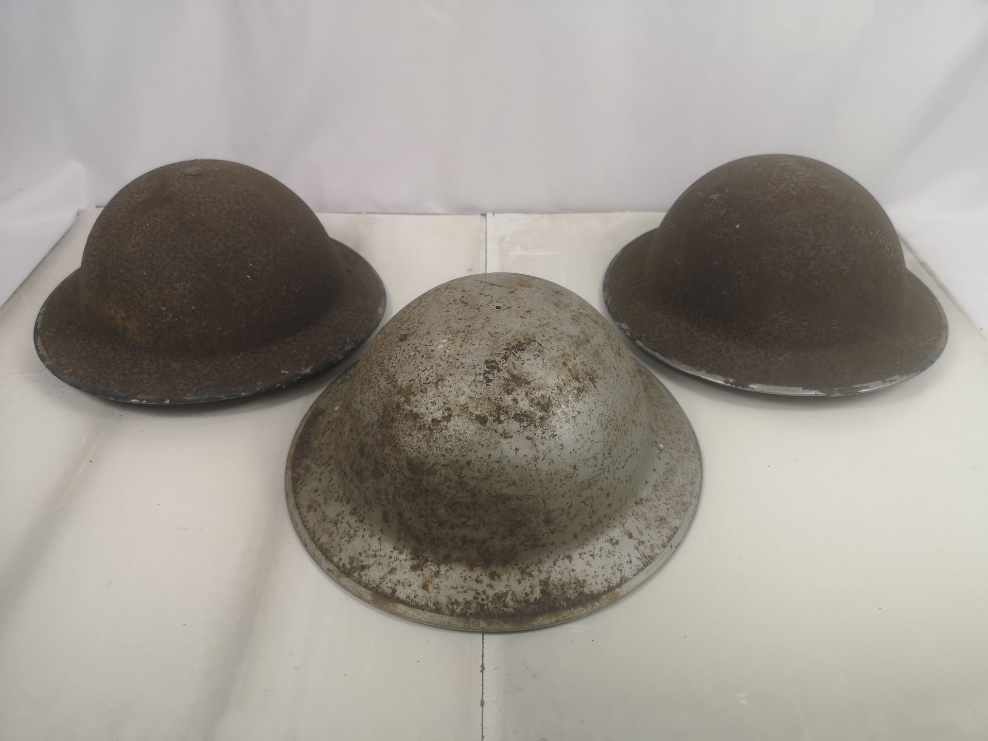 Three WWII steel military helmets.