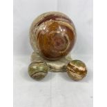 An onyx ball on marble base together with two smaller balls