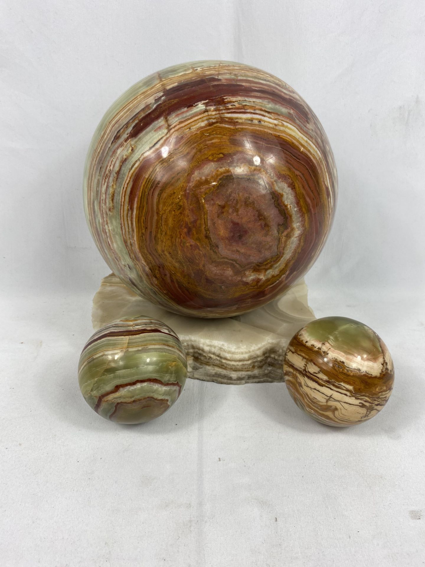 An onyx ball on marble base together with two smaller balls