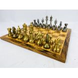 A metal chess set; a wood chess set, and wood chess board