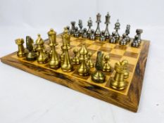 A metal chess set; a wood chess set, and wood chess board