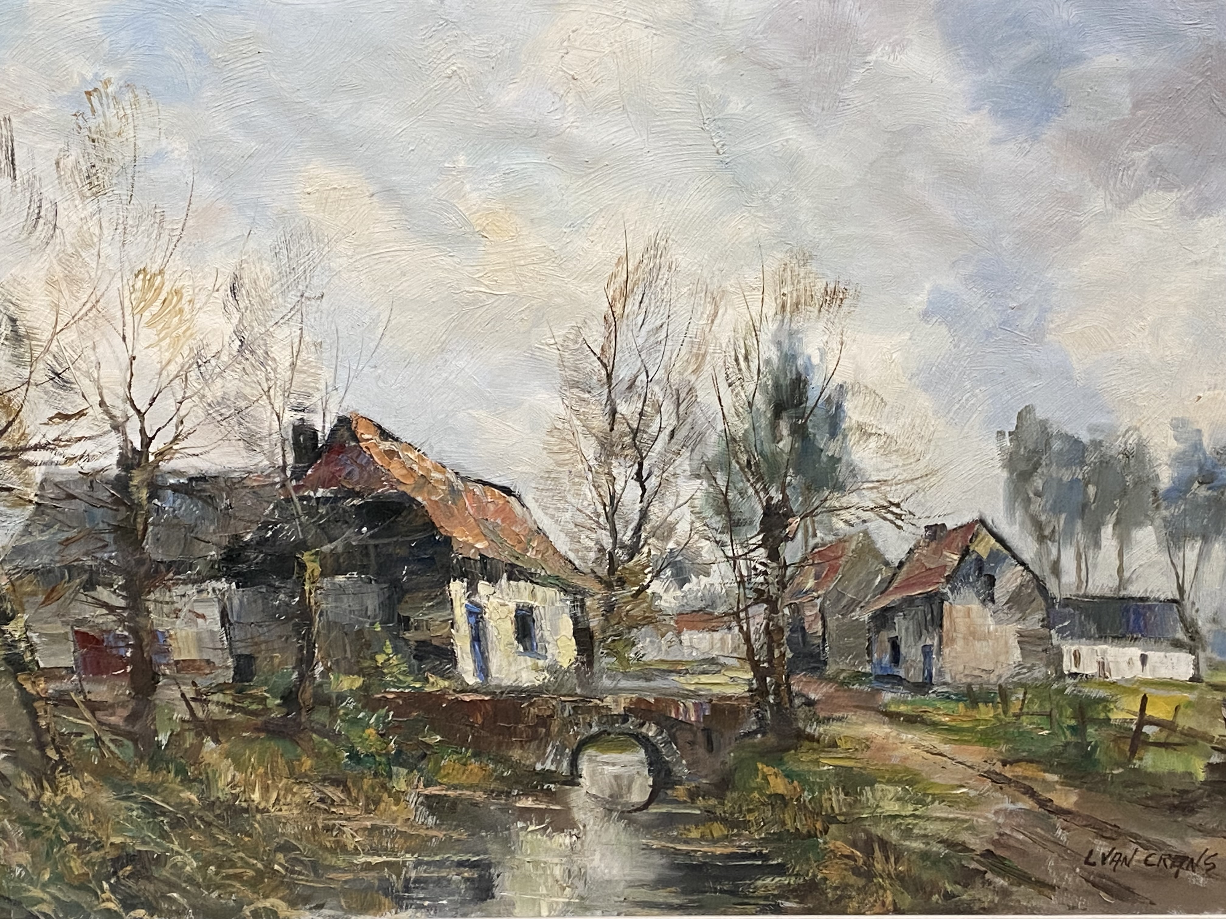 Framed oil on canvas of a village in winter, signed L Van Crans