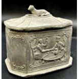 Georgian lead tea caddy, relief decoration of a tavern scene and recumbent hound to lid, 13cm high