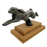 Silvered bronze car mascot in the form of a leaping hare, on stepped oak plinth, 11cm high x 18cm