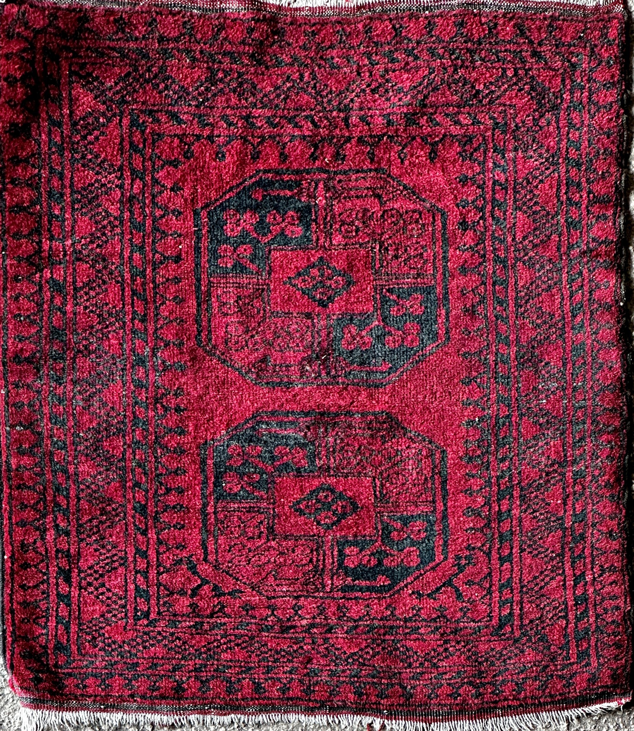 Full pile Bokhara rug, two black medallions on a red ground, 120 x 105cm