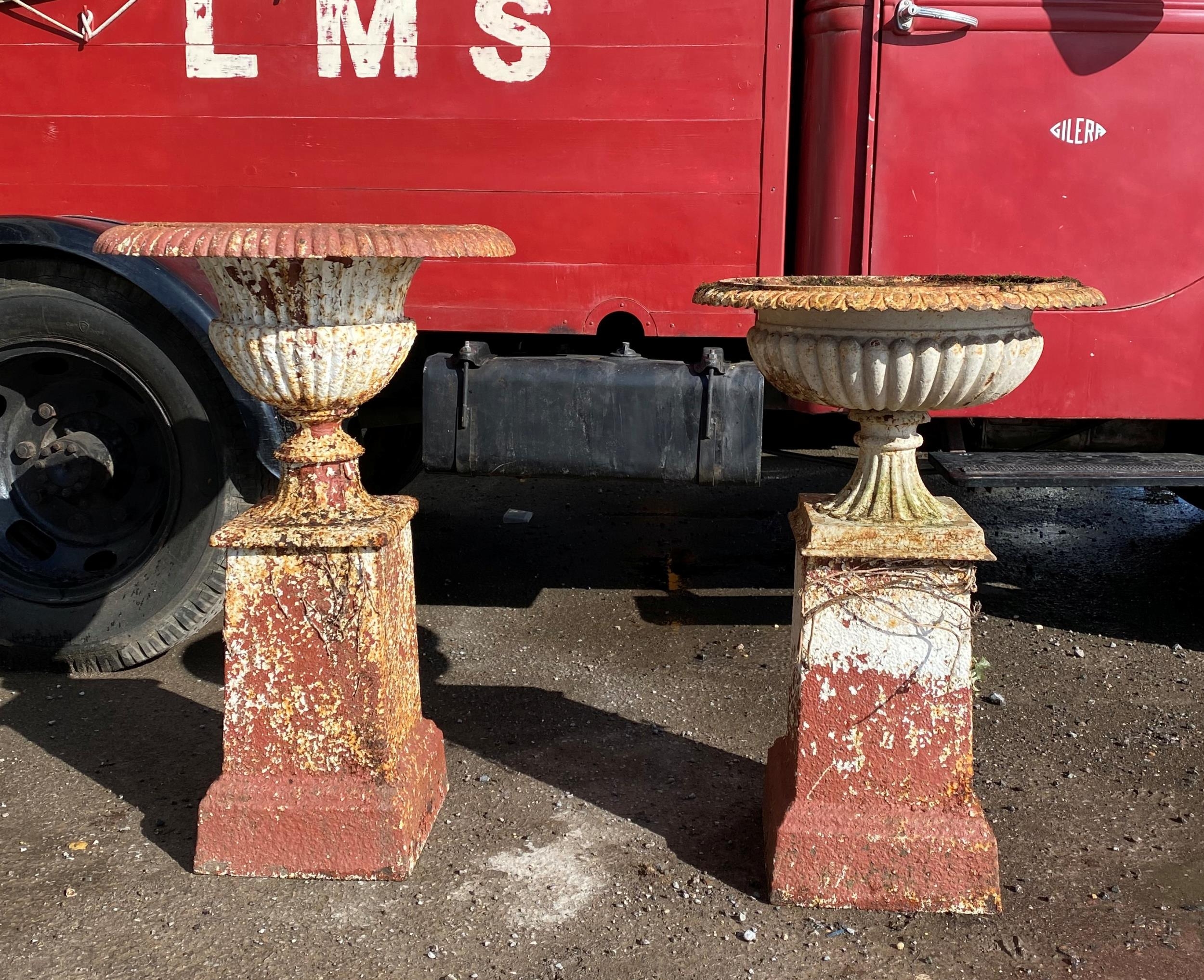 Matched pair of cast iron urns on associated columns, 86cm high approx