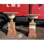 Matched pair of cast iron urns on associated columns, 86cm high approx