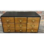 Vintage Industrial table top bank of nine drawers, with brass fittings in an ebonised case, 43cm