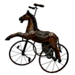 Carved horse tricycle, with good patina leather saddle and iron wheels and