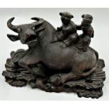 Carved Chinese hardwood figural group of two children sat on an ox, on a fitted naturalistic base,
