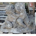 Antique weathered reconstituted stone garden ornament in the form of cherubs embracing, 50cm high
