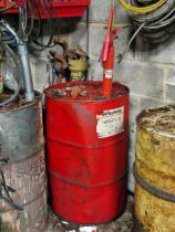 Three barrels of tractor engine oil with oil pumps, one full the other two partially filled, the