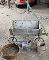 Vintage wooden wheelbarrow 41cm high x 90cm wide together with two galvanised watering cans and a