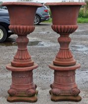 Pair of reconstituted stone garden urns with lobed bowls and flared rims, raised on Corinthian