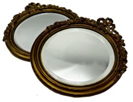 Pair of continental ormolu framed tondo wall mirrors with original bevelled glass mounted by a