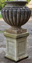 Weathered stone garden urn with gadrooned detail raised on a square pedestal base, 105cm high