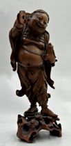 Carved Japanese hardwood figure of a rotund dancing gentleman holding a lizard in one hand and a
