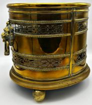 Good 19th century brass oval log bin with twin cast lionhead ring handles, pierced Celtic bands