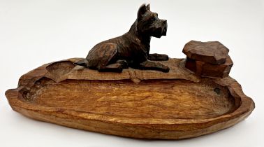 Black Forest style carved wooden desk standish mounted by a recumbent terrier, with revolving top