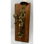 Cast brass figural sconce, modelled as a cherub, upon a fruitwood plaque, 41cm high