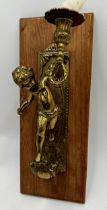 Cast brass figural sconce, modelled as a cherub, upon a fruitwood plaque, 41cm high